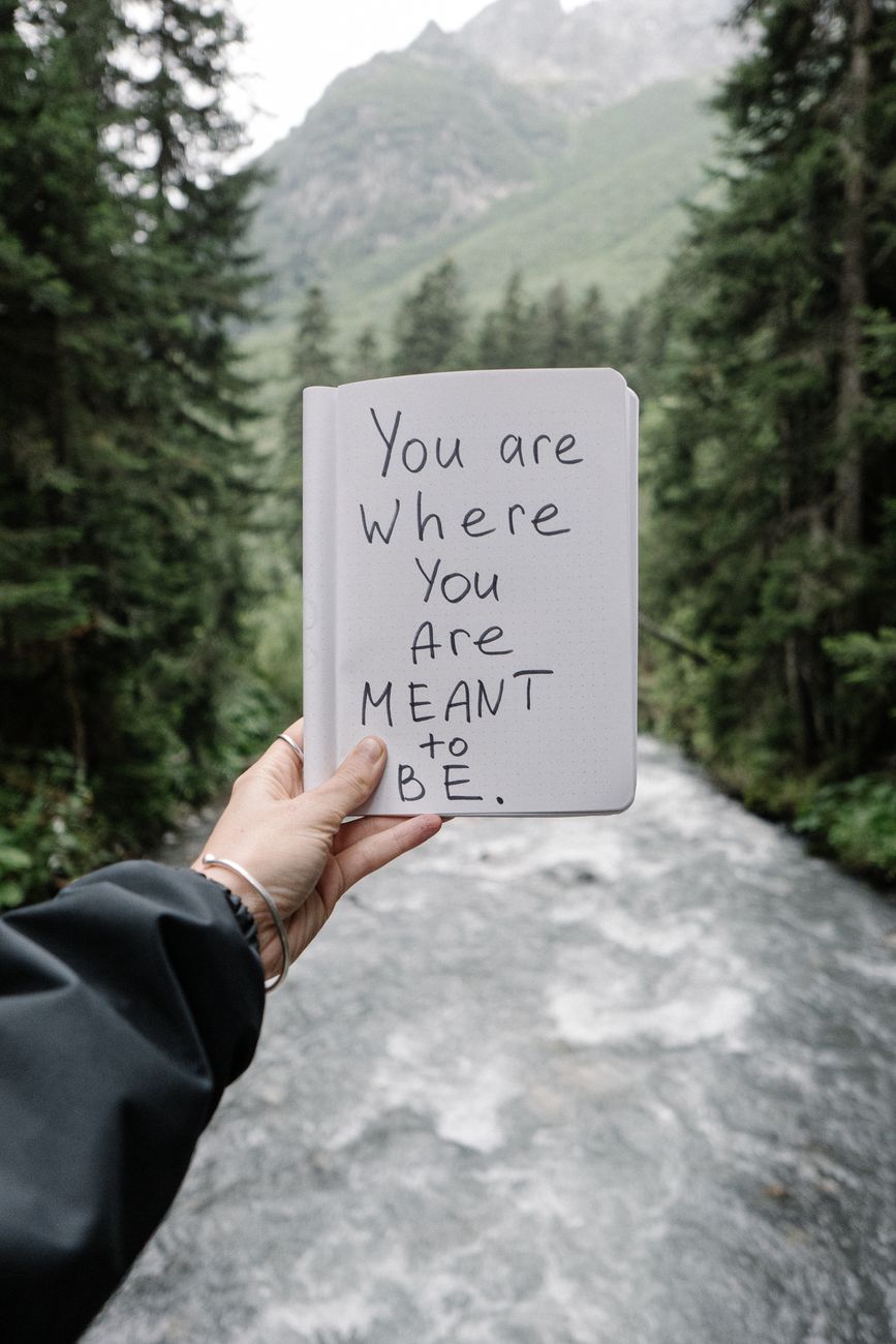 quote on notepad page in hand over river